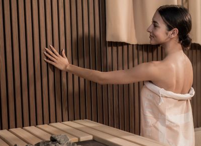 Frau steht vor einer Wand und Ofen in Sauna
