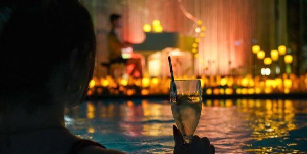 Siluette einer Person im Wasser mit Cocktail, Kerzenschein im Hintergrund