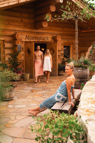 Frau sitzt auf einer Bank vor der Alpenglück Sauna 