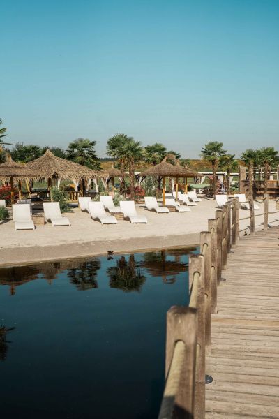 Ein Steg der zu einem Strand mit Liegen führt