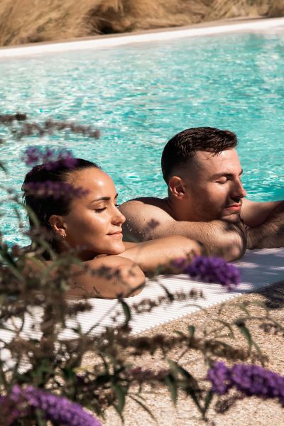 zwei Personen entspannen in einem Pool mit türkisenem Wasser