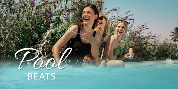 Drei Personen sitzen am Pool-Rand und lachen