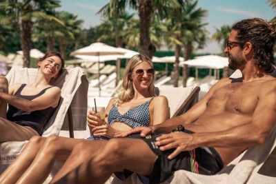 Zwei Frauen und ein mann sitzen am Strand und lachen