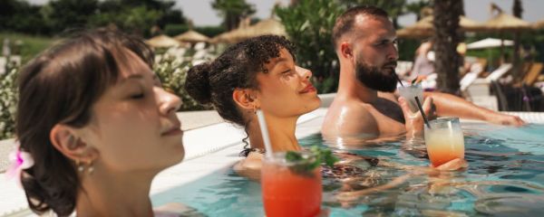 drei Personen liegen in Pool mit Cocktails