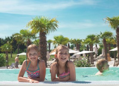 drei Personen lachen und sitzen am Poolrand