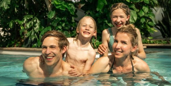 zwei Eltern heben ihre Kinder im Wasser hoch