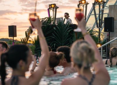 zwei personen schwimmen in einem pool mit cocktails bei einem event