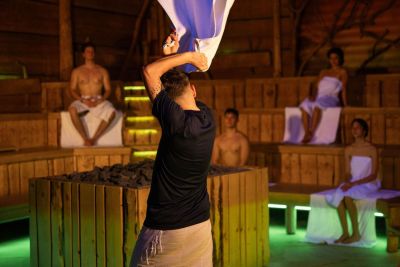 Person wedelt mit Handtuch in einer Sauna.