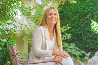 A woman is sitting on a bench in a park.