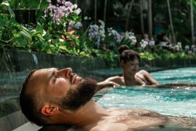 A man is relaxing in a lagoon, and a woman can be seen in the background.