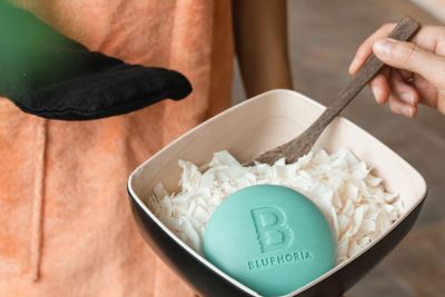 A bowl containing fine soap flakes and a round blue bar of soap bearing the inscription ‘Bluphoria’