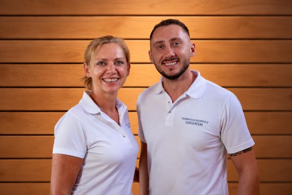 Ein Mann und eine Frau stehen vor einer Holzwand